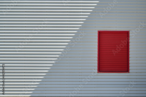 Red window on white industrial metallic textured facade