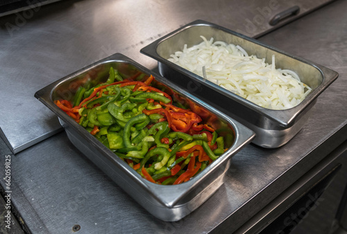 Two metal containers, one with cut onions and the other with cut peppers in the kitchen of a pizza shop in Monroeville, Pennsylvania, USA photo