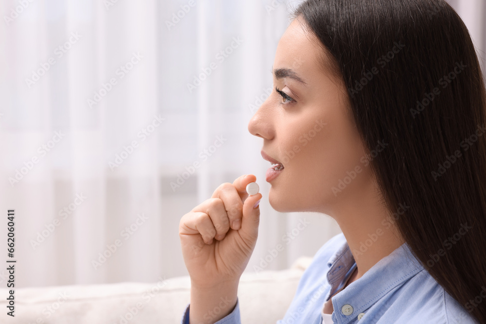Beautiful young woman taking pill at home, space for text Beautiful young woman taking pill at home, space for text