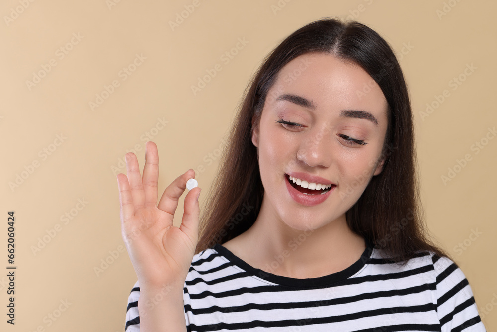 Happy woman showing pill on beige background Happy woman showing pill on beige background