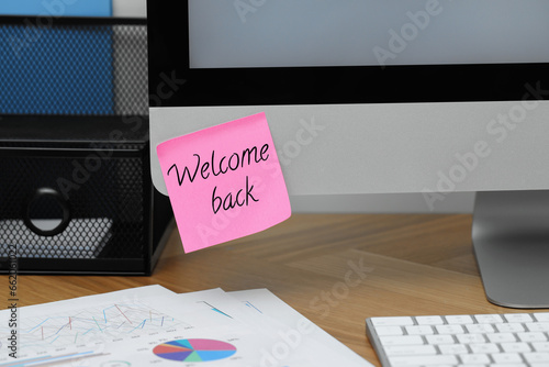 Sticky note with phrase Welcome Back on computer monitor in office photo