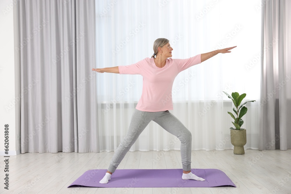 Senior woman practicing yoga on mat at home Senior woman practicing yoga on mat at home
