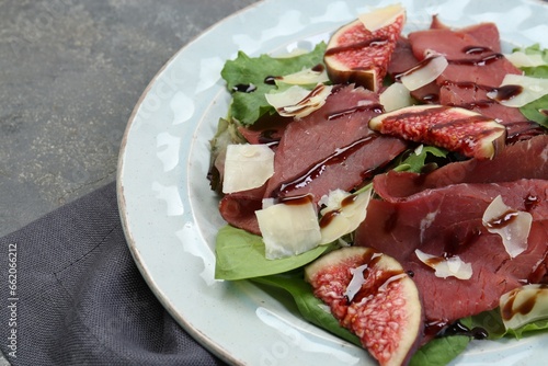 Plate with delicious bresaola salad on grey textured table, closeup