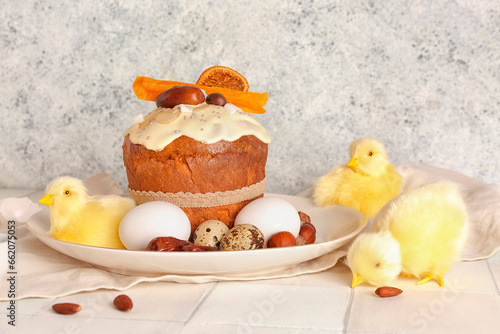 Easter cake with chicken figures and eggs on white tile table near light grunge wall © Pixel-Shot