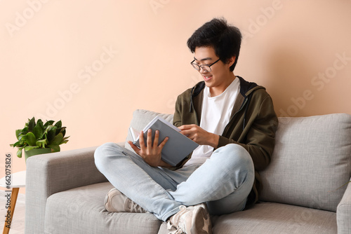Young Asian man reading boo...