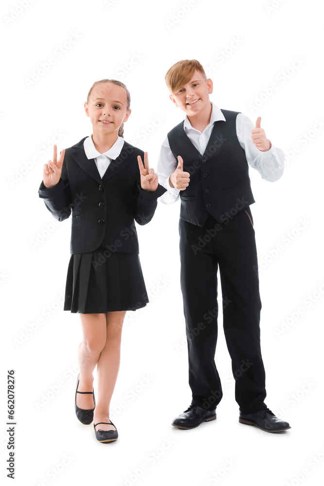 Little classmates in stylish uniform with backpacks showing thumbs-up gesture on white background Little classmates in stylish uniform with backpacks showing thumbs-up gesture on white background