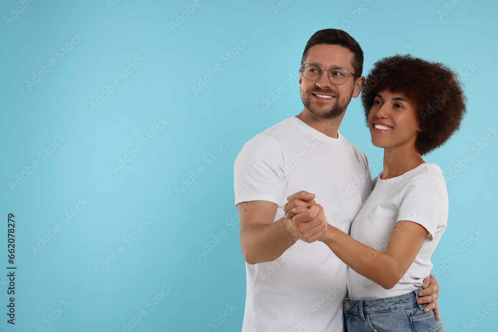 International dating. Happy couple dancing on light blue background, space for text International dating. Happy couple dancing on light blue background, space for text
