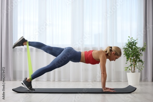 Athletic woman doing exercise with fitness elastic band on mat at home photo