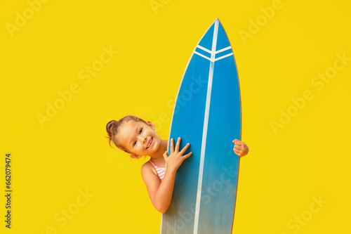 Little girl with surfboard on yellow background