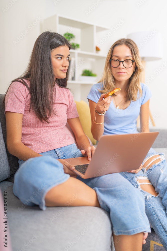 Students eating pizza while using laptop at home Students eating pizza while using laptop at home