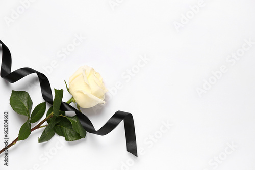 Black mourning ribbon and rose on white background