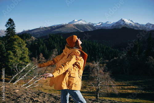 Woman in full height hiker standing with her back up and back on the mountain of happiness in yellow raincoat travel autumn and hiking in the mountains in the sunset freedom © SHOTPRIME STUDIO