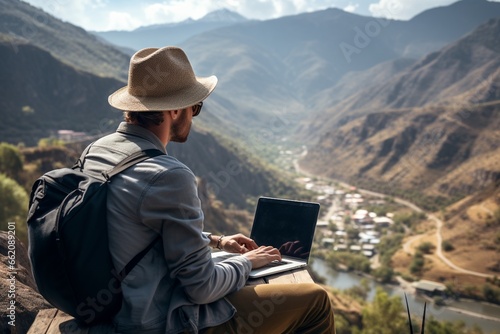 Digital nomad working on a laptop with a breathtaking mountain view created with Generative AI © dendyh7