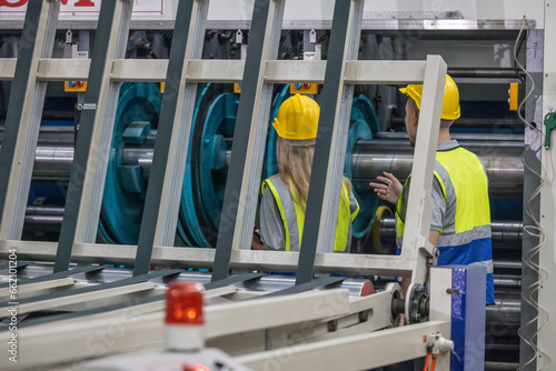 Techs inspecting, maintaining cardboard machine for safety, uninterrupted, high-quality production.