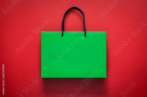 Green shopping paper bag on red background for Black Friday shopping sale concept.