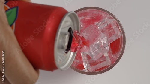 Pouring red Fanta juice over ice