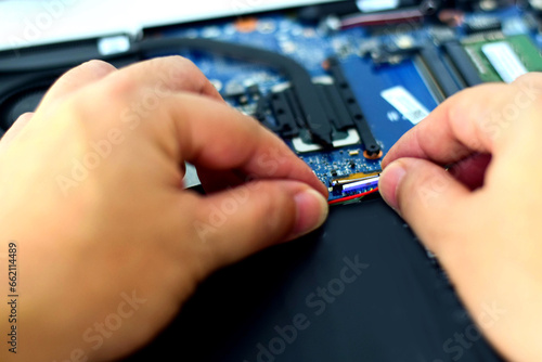 computer technician laptop motherboard repair technician Removing the battery cable connector from the notebook computer motherboard.