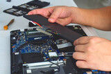computer technician laptop motherboard repair technician Removing the battery from the notebook computer