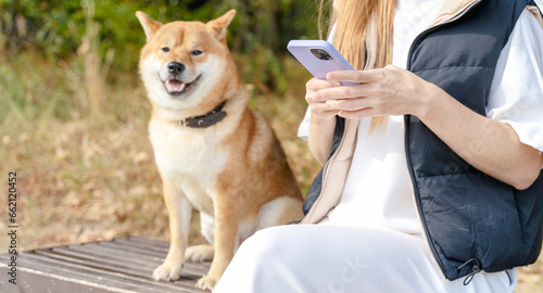 a girl in the park with a dog and a smartphone