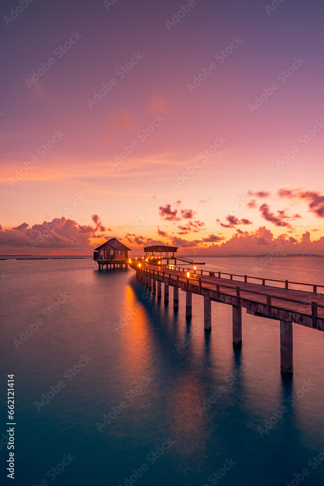 Fototapeta premium Amazing sunset panorama Maldives. Luxury resort villas pier path seascape soft led lights under colorful sky. Beautiful twilight sky fantastic clouds. Majestic beach background best vacation holiday