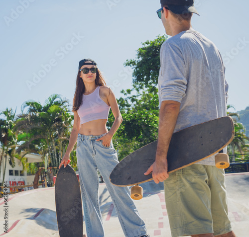 Young happy couple with skateboards enjoy longboarding at the skatepark photo