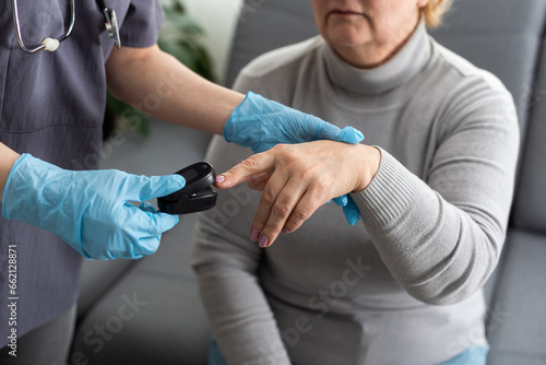 Therapist attaches pulse oximeter to the finger of elderly patient.