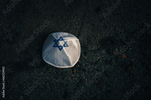 knitted kippah cap in Israeli flag style on a dark asphalt road background photo