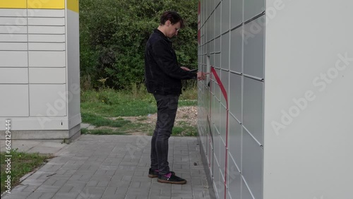 a man picks up a parcel at a Post terminal / parcel locker photo