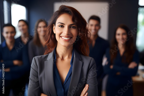 Leading with Confidence A Smiling, Attractive Professional Woman Strikes a Pose in Her Business Office, Surrounded by Her Coworkers and Employees in the Background