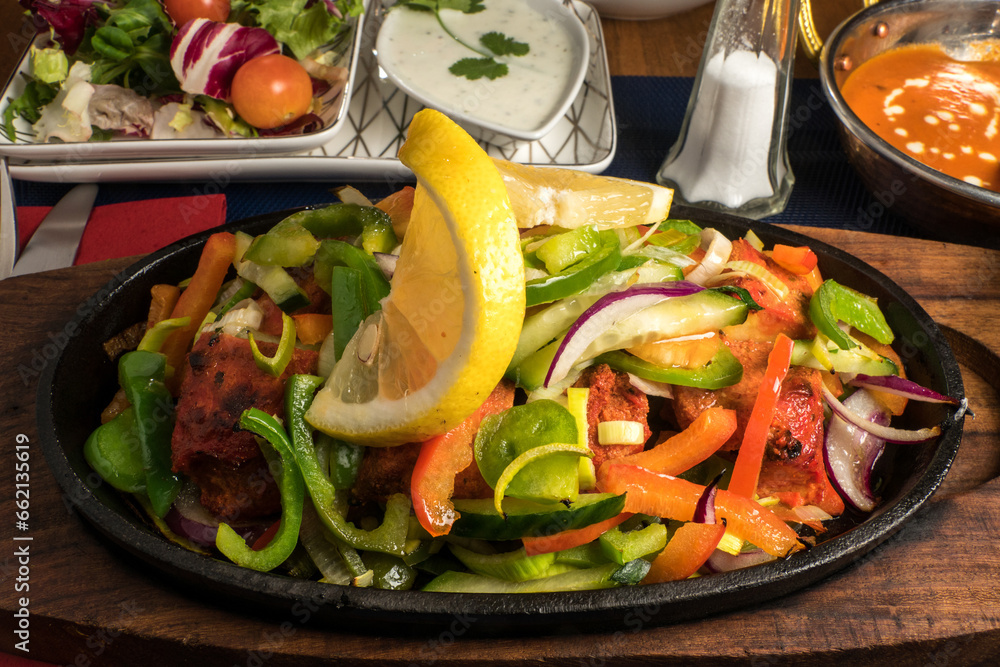 A chicken sizzler dish with chicken and vegetables. A chicken sizzler dish with chicken and vegetables.