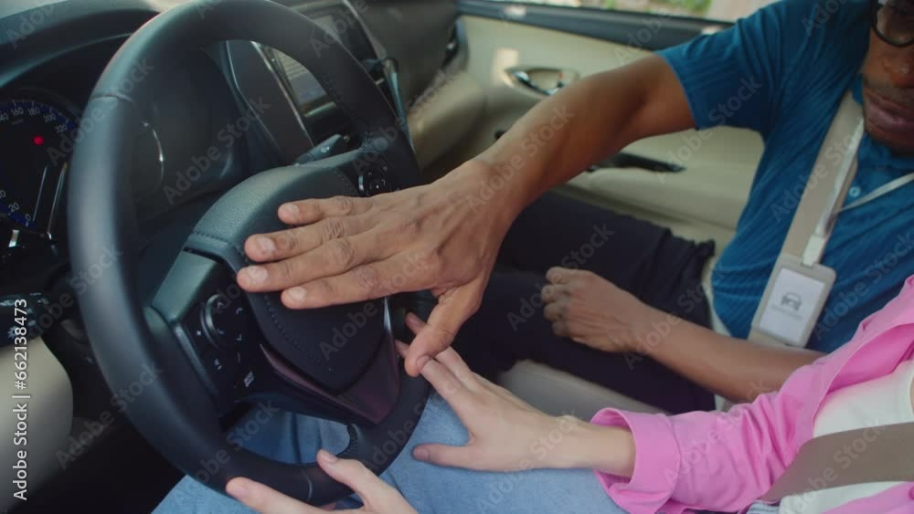 Cropped shot of driving teacher explaining steering wheel operation principle to his student while sitting inside car during lesson Cropped shot of driving teacher explaining steering wheel operation principle to his student while sitting inside car during lesson
