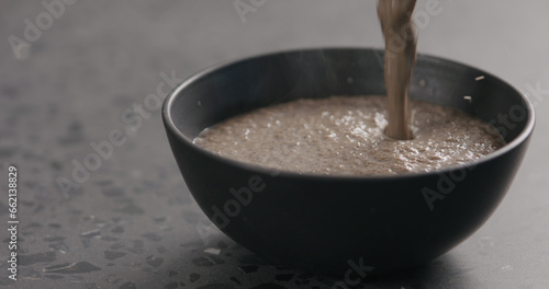 Closeup photo of fresh hot mushroom cream soup in black ceramic bowl with copy space