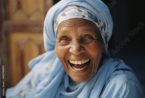 a dark-skinned older woman laughing happily with a traditional headscarf and clothes