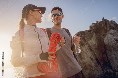 Young couple climbs with a rope to the top in the mountains near the ocean