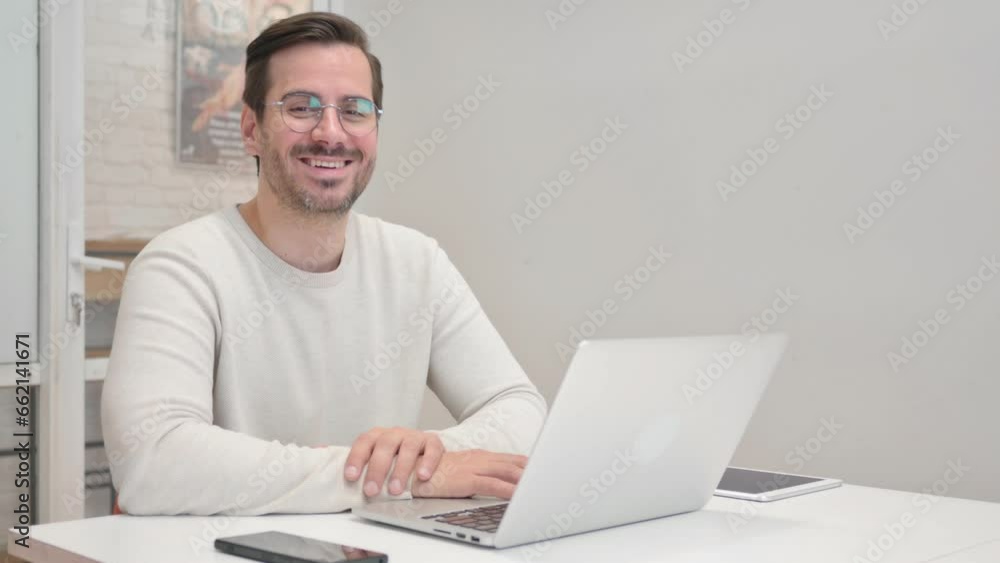 Middle Aged Man Smiling at Camera while Working on Laptop in Office Middle Aged Man Smiling at Camera while Working on Laptop in Office