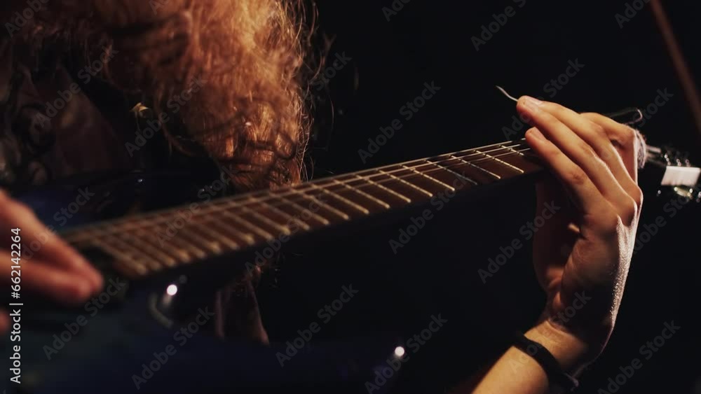 Stageside Riff Long-haired guitarist close up playing the riff on an electric guitar ...