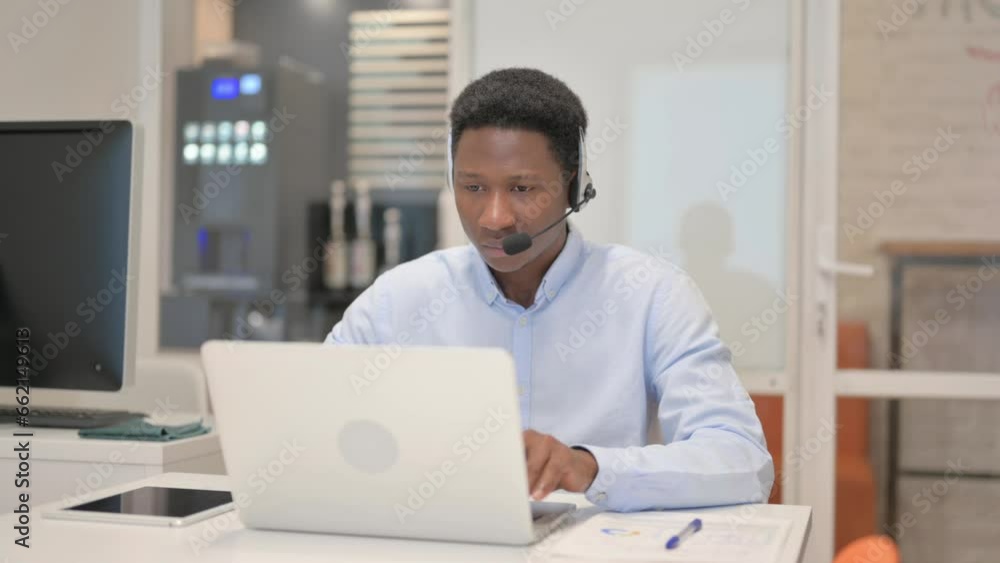 African Man with Headset Working on Laptop in Call Center African Man with Headset Working on Laptop in Call Center