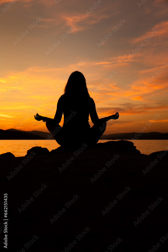 sylwetka kobiety medytującej na plaży przy zachodzie słońca - obrazy, fototapety, plakaty 