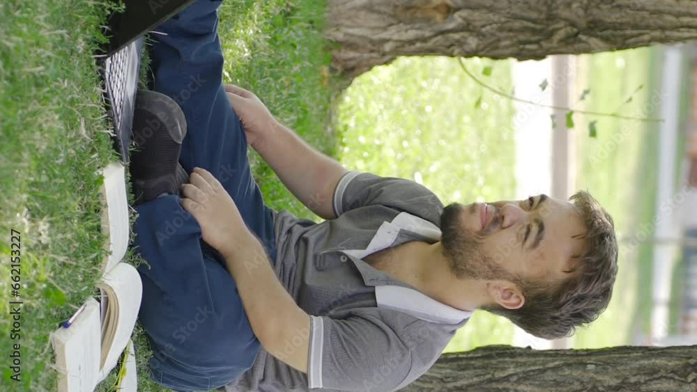 Vertical Video of University dwarf student who is bored with studying is sitting outdoors.