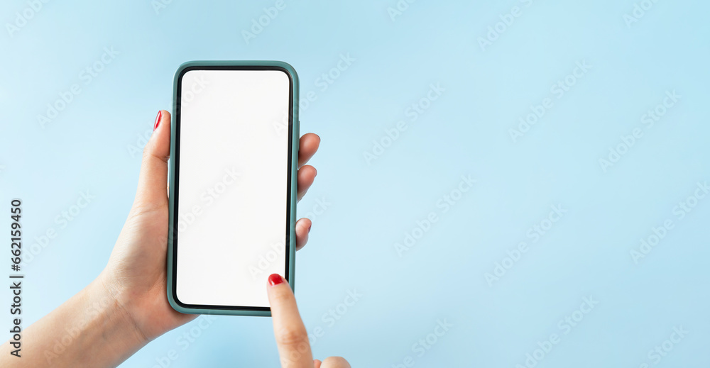Female hands holding smartphone with mockup of blank screen on blue background.
