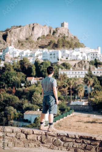 Man in travel, Asian man standing on the edge, looking at the old city, Zahara de la Sierra in Cadiz, Spain