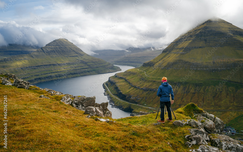 A photographer with a camera on a viewpoint during an adventure in the Faroe Islands. Capturing moments of breathtaking beauty