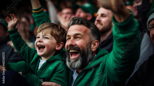 Irish father and son in stands, filled with enthusiastic supporters of rugby or football team wearing green clothes to support national sports team