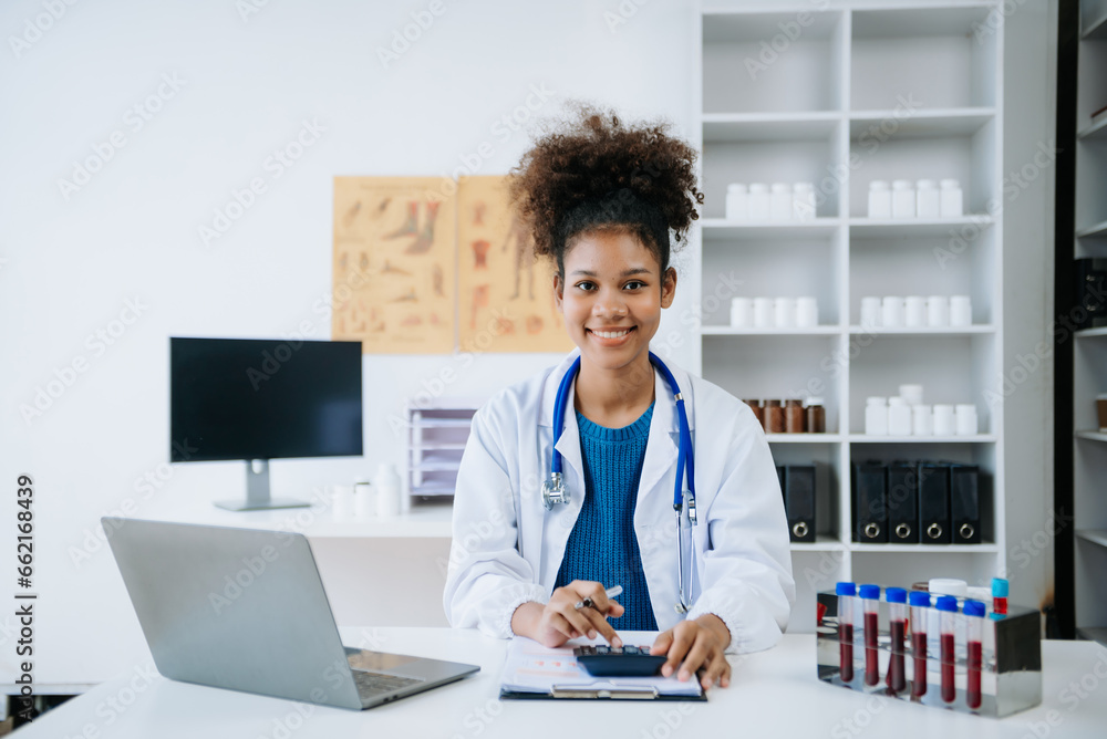 Beautiful physician doctor sit on table in office hospital. Attractive therapist female practitioner pharmacist smile and use tablet and laptop in hospital.after success work from treatment. Beautiful physician doctor sit on table in office hospital. Attractive therapist female practitioner pharmacist smile and use tablet and laptop in hospital.after success work from treatment.