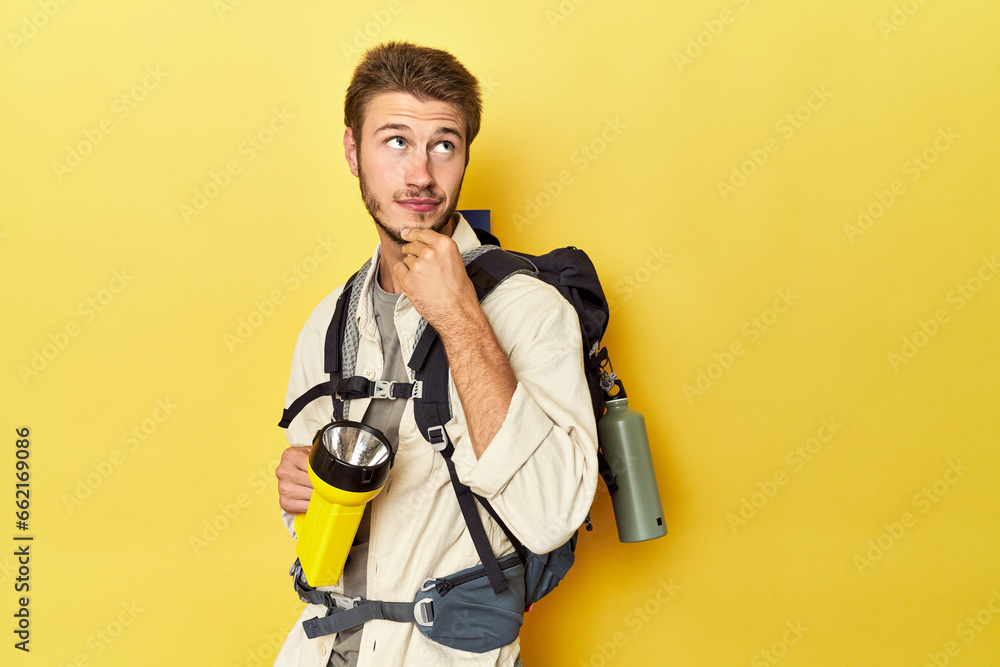 Traveler with mountain backpack and torch looking sideways with doubtful and skeptical expression. Traveler with mountain backpack and torch looking sideways with doubtful and skeptical expression.