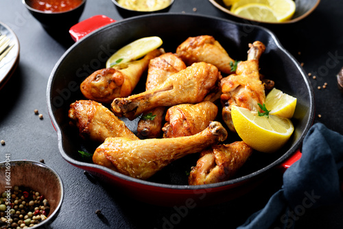 Juicy Oven Roasted Chicken legs in red iron pan.  Black background