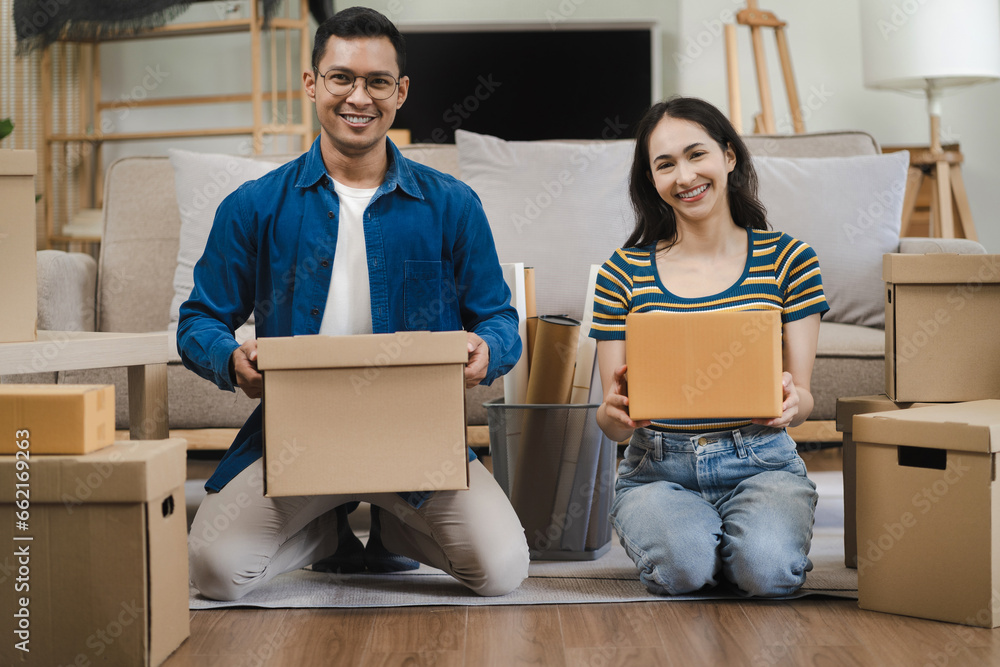 Young couple relaxing sitting on the floor around cardboard boxes at home, smiling happy moving to a new house. Young couple relaxing sitting on the floor around cardboard boxes at home, smiling happy moving to a new house.