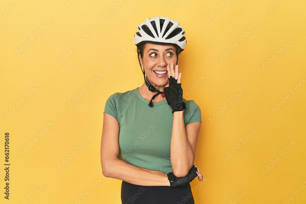 Cyclist middle aged woman with helmet and gloves posed is saying a secret hot braking news and looking aside Cyclist middle aged woman with helmet and gloves posed is saying a secret hot braking news and looking aside