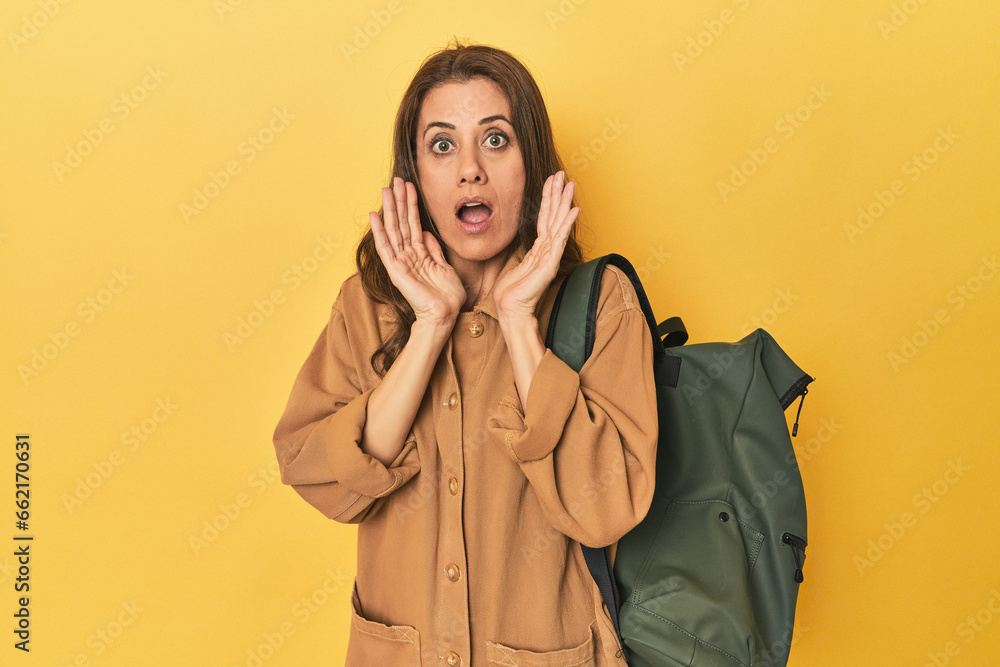 Middle aged woman prepped for hiking, yellow studio shot surprised and shocked. Middle aged woman prepped for hiking, yellow studio shot surprised and shocked.