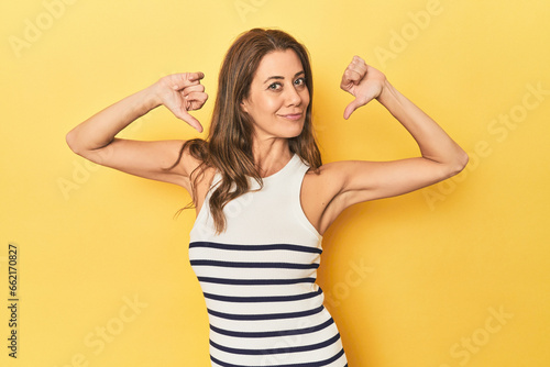 Middle-aged caucasian woman on yellow feels proud and self confident, example to follow.